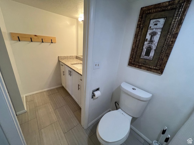 bathroom featuring baseboards, vanity, and toilet
