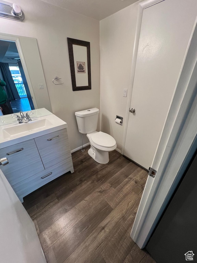 bathroom with baseboards, wood finished floors, vanity, and toilet