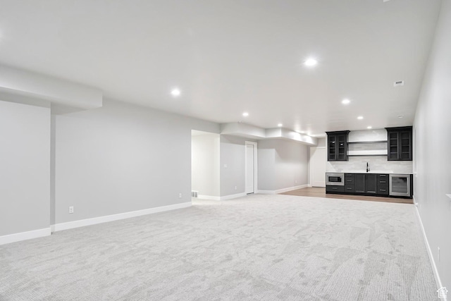 unfurnished living room featuring light colored carpet, wet bar, beverage cooler, baseboards, and recessed lighting