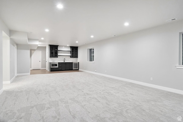 unfurnished living room featuring recessed lighting, baseboards, a sink, visible vents, and indoor wet bar
