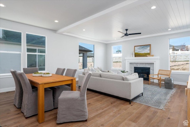 living area featuring wood finished floors, a glass covered fireplace, baseboards, ceiling fan, and recessed lighting