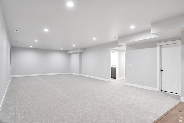 finished basement featuring visible vents, baseboards, light colored carpet, and recessed lighting