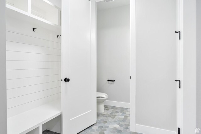 full bathroom with toilet, tiled shower, and baseboards