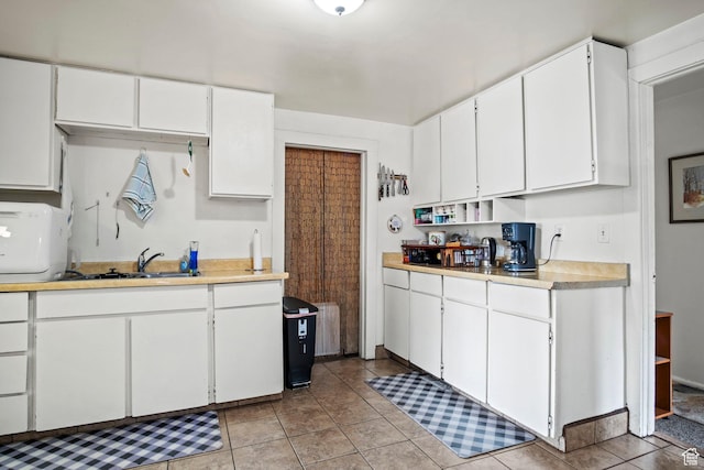 kitchen with light tile patterned floors, sink, and white cabinets