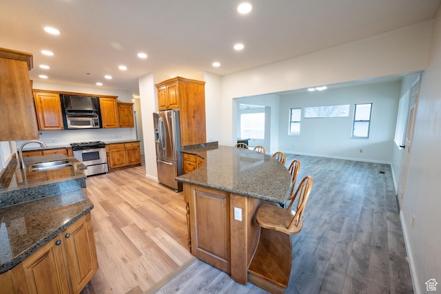 kitchen with a kitchen breakfast bar, sink, appliances with stainless steel finishes, and dark stone counters