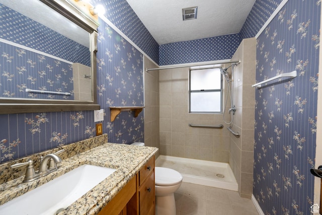 bathroom with vanity, tile patterned floors, toilet, a textured ceiling, and a tile shower