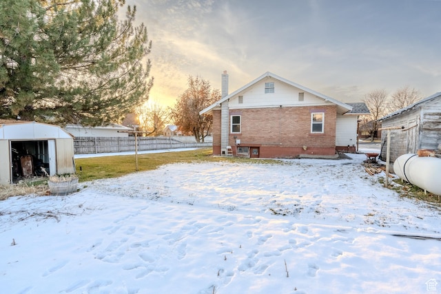 snow covered rear of property with a storage shed