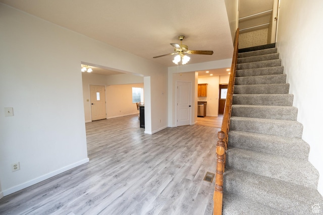stairs featuring ceiling fan and hardwood / wood-style flooring