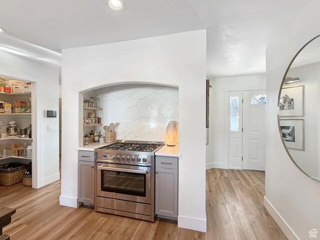 kitchen with light wood-style floors, high end range, light countertops, and gray cabinetry