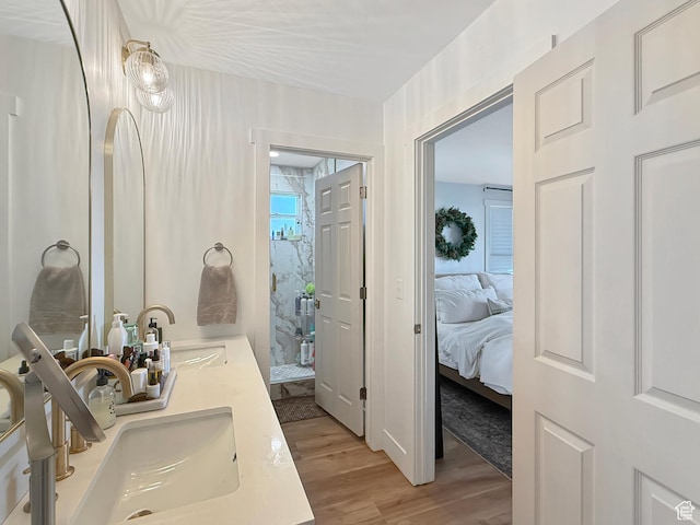 ensuite bathroom with double vanity, wood finished floors, ensuite bath, and a sink