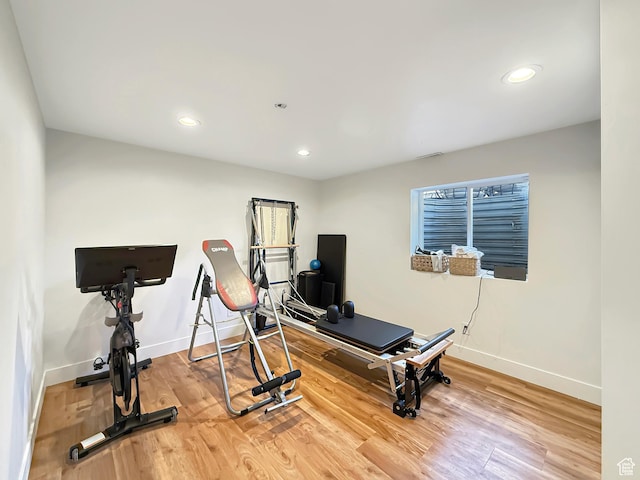 exercise room with baseboards, wood finished floors, and recessed lighting