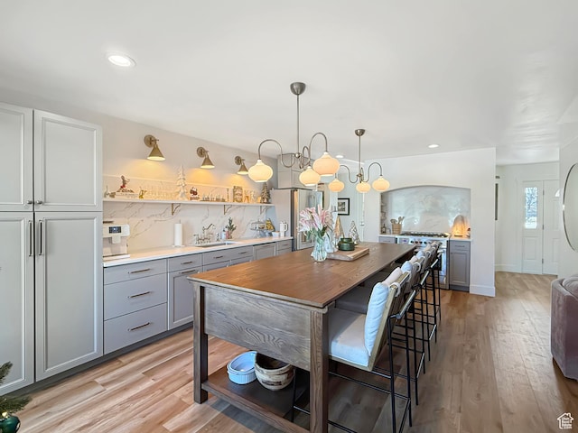 kitchen with light wood-style floors, appliances with stainless steel finishes, decorative backsplash, and gray cabinetry