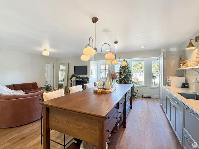 kitchen with open floor plan, open shelves, a sink, and light wood-style floors