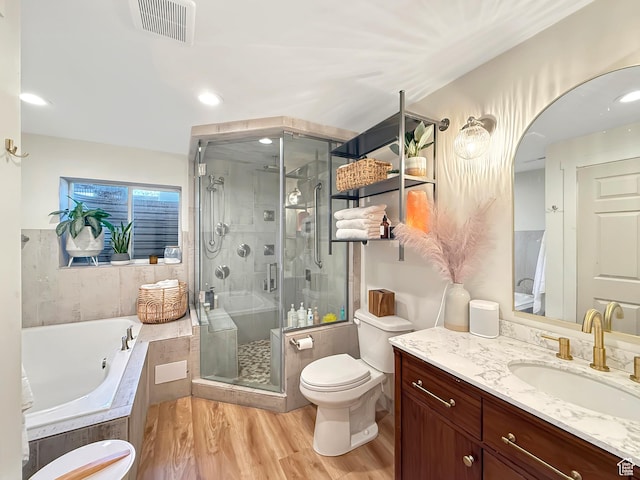bathroom with a garden tub, toilet, wood finished floors, vanity, and visible vents