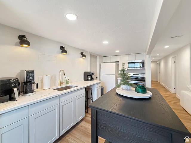kitchen with light wood-style flooring, appliances with stainless steel finishes, a sink, and recessed lighting