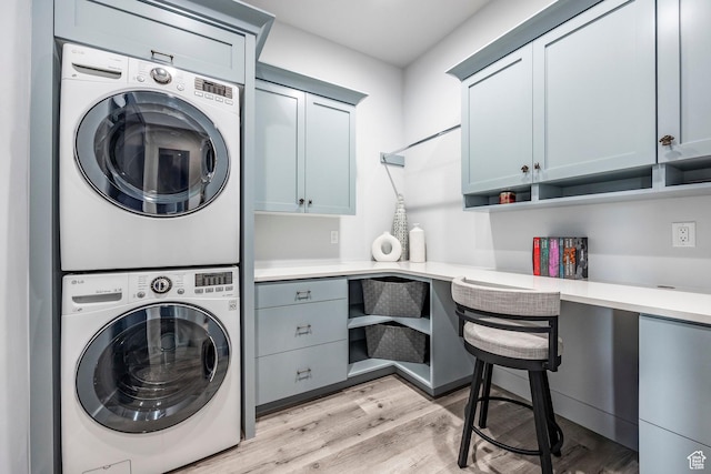 laundry area with light hardwood / wood-style flooring, cabinets, and stacked washer and clothes dryer