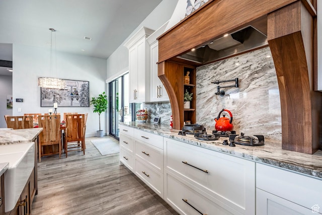 kitchen with backsplash, white cabinetry, hanging light fixtures, and premium range hood