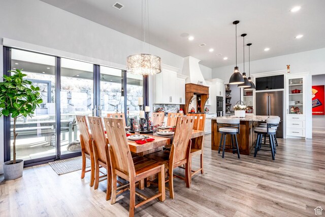 dining area featuring a notable chandelier, a healthy amount of sunlight, and light hardwood / wood-style flooring