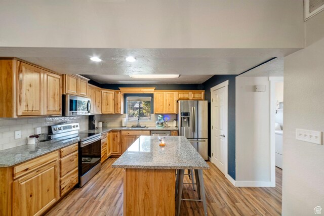 55 E 700 S Unit 1, St George, UT 84770 - kitchen featuring a center island, light stone countertops, light wood-type flooring, a kitchen bar, and stainless steel appliances