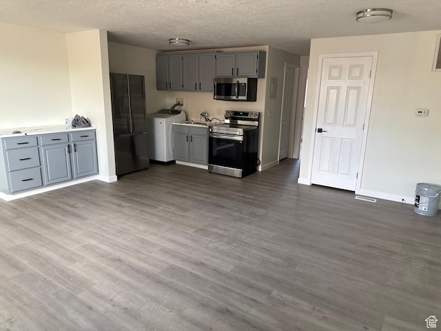 3671 S 2200 W Unit 1, West Valley City, UT 84119 - kitchen featuring stainless steel appliances, wood-type flooring, a textured ceiling, washer / dryer, and gray cabinets