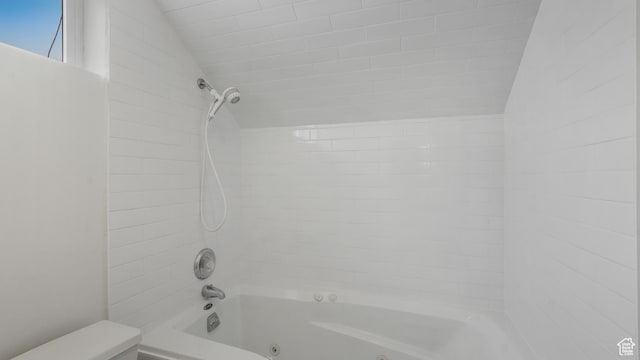 bathroom with tiled shower / bath and vaulted ceiling