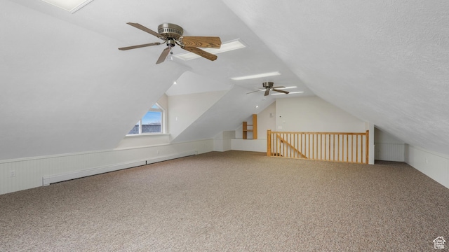 bonus room with carpet flooring, ceiling fan, baseboard heating, vaulted ceiling, and a textured ceiling