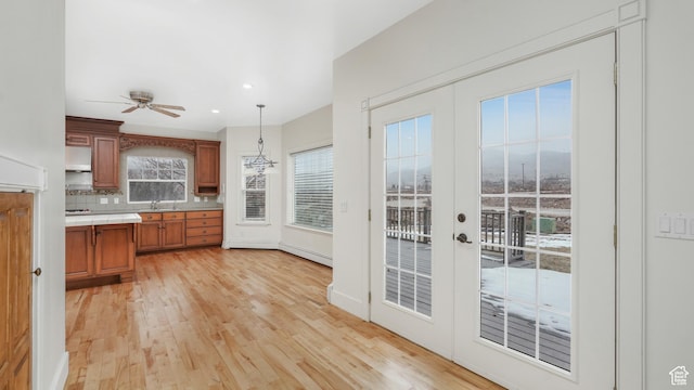 kitchen featuring french doors, tasteful backsplash, ceiling fan, pendant lighting, and light hardwood / wood-style flooring