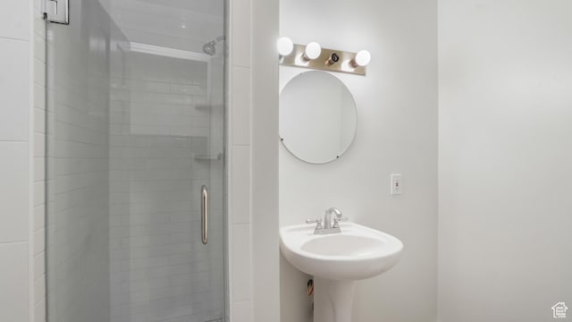 bathroom with a shower with door and sink
