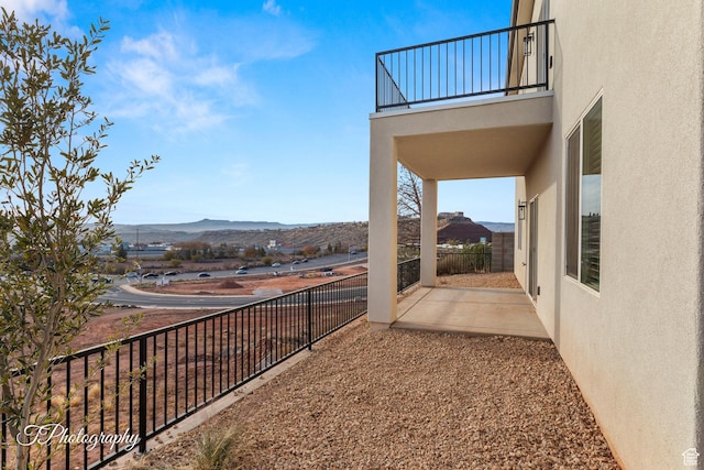 view of yard featuring a mountain view, a patio area, and a balcony