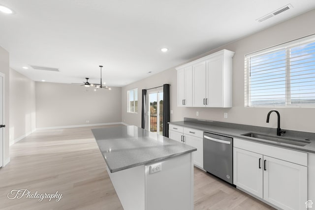 kitchen featuring dishwasher, a center island, sink, light hardwood / wood-style flooring, and white cabinetry