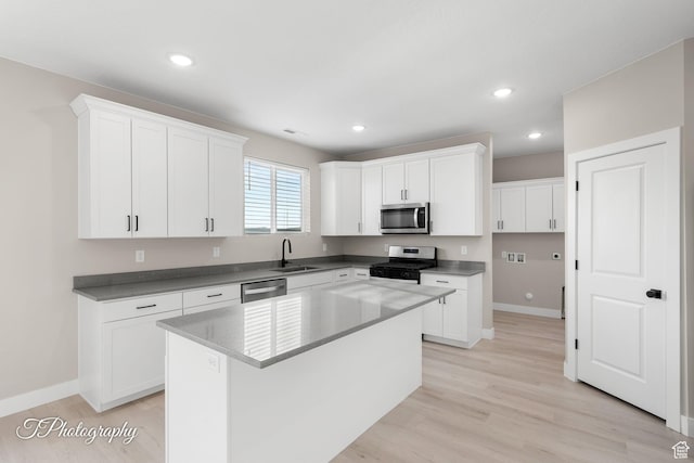 kitchen featuring sink, light hardwood / wood-style flooring, a kitchen island, white cabinetry, and stainless steel appliances