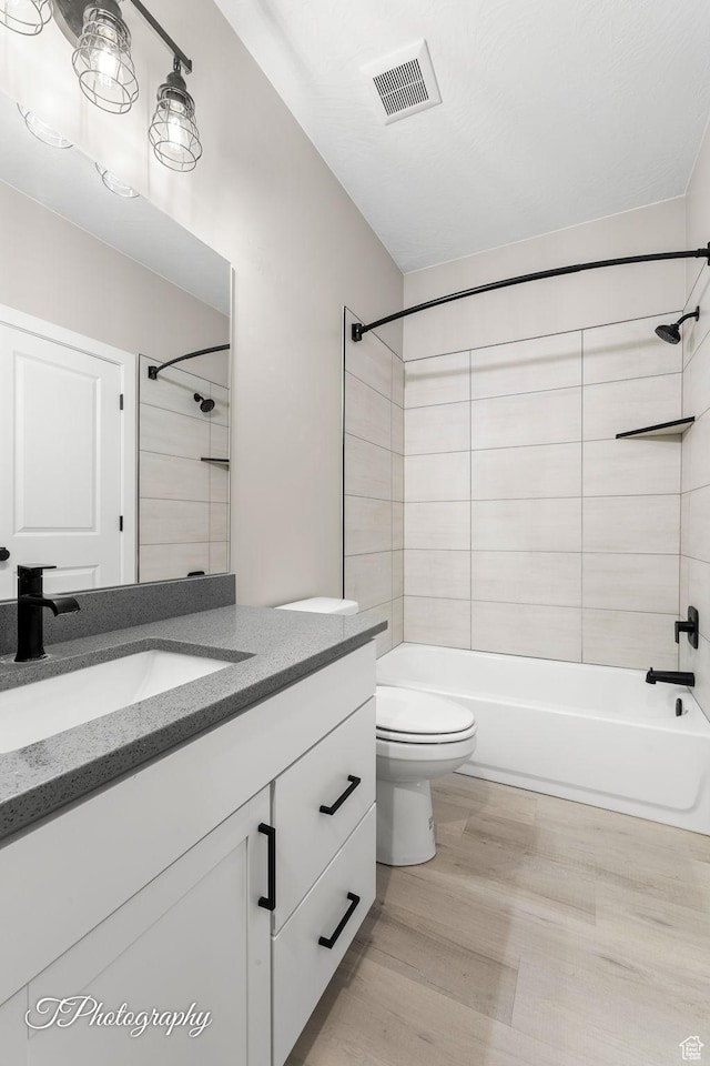 full bathroom featuring wood-type flooring, vanity, toilet, and tiled shower / bath