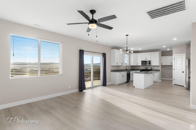 kitchen with ceiling fan with notable chandelier, stainless steel appliances, a center island, white cabinetry, and hanging light fixtures