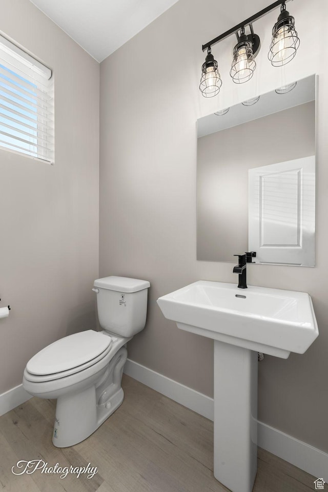bathroom with toilet, wood-type flooring, and sink
