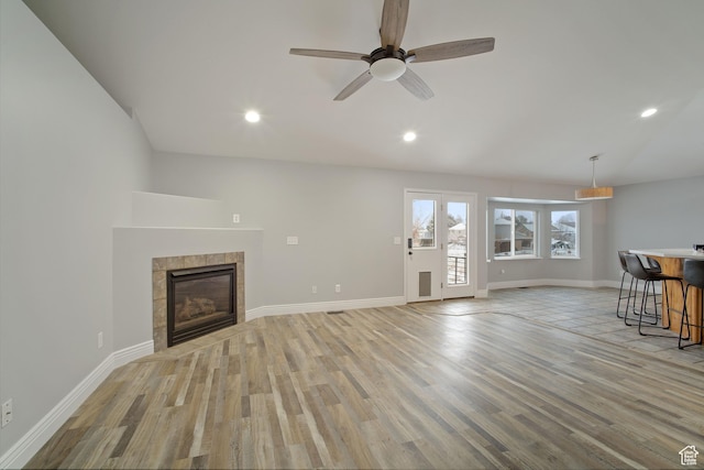 6190 W 5950 S, Hooper, UT 84315 - unfurnished living room featuring a tiled fireplace, ceiling fan, and light wood-type flooring