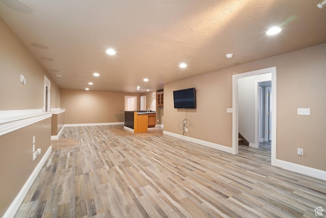 6190 W 5950 S, Hooper, UT 84315 - unfurnished living room featuring light hardwood / wood-style flooring, a textured ceiling, and sink