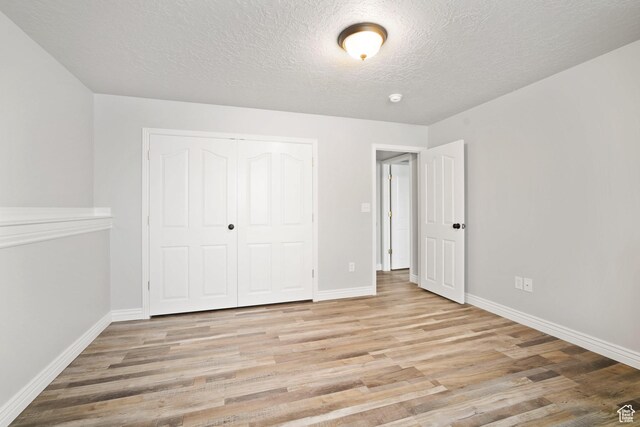 6190 W 5950 S, Hooper, UT 84315 - unfurnished bedroom with a textured ceiling, light wood-type flooring, and a closet