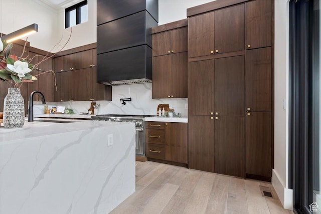 1316 N Gold Mountain Cir, Heber City, UT 84032 - kitchen with high end stainless steel range oven, light wood-style flooring, a sink, modern cabinets, and light stone counters