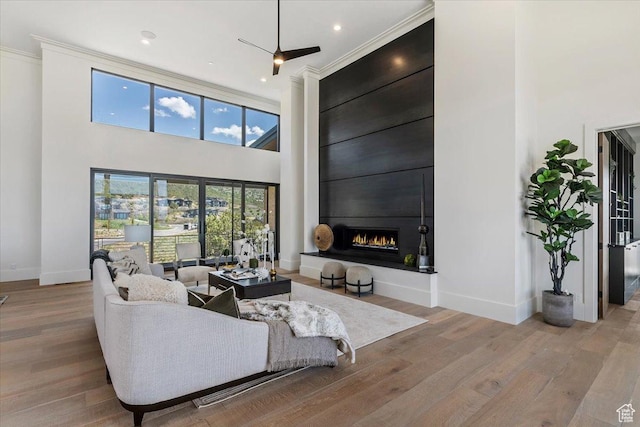 1316 N Gold Mountain Cir, Heber City, UT 84032 - living area featuring a towering ceiling, baseboards, wood finished floors, a large fireplace, and crown molding