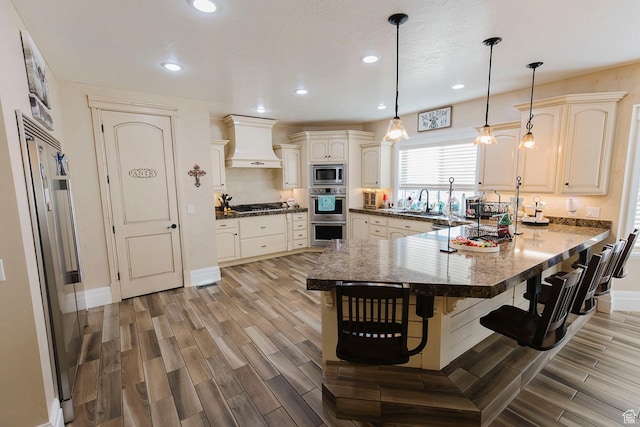 743 N 1100 E, Nephi, UT 84648 - kitchen with a peninsula, built in appliances, custom range hood, a breakfast bar, and wood finish floors