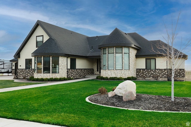 french country inspired facade featuring stone siding, a shingled roof, a front yard, and stucco siding