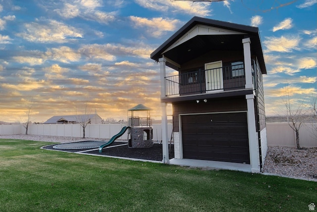 743 N 1100 E, Nephi, UT 84648 - back of house at dusk featuring a playground, fence, an attached garage, a lawn, and a balcony