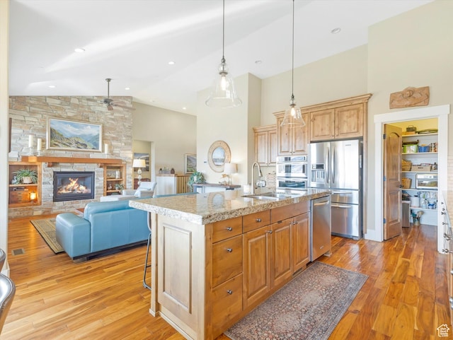 1628 E Viewside Cir, Hideout, UT 84036 - kitchen featuring sink, light stone counters, a fireplace, a center island with sink, and appliances with stainless steel finishes