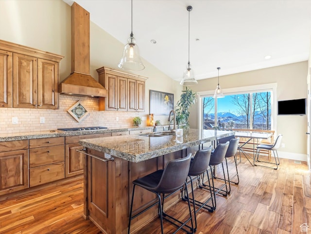 1628 E Viewside Cir, Hideout, UT 84036 - kitchen featuring light stone countertops, custom exhaust hood, a breakfast bar area, lofted ceiling, and an island with sink