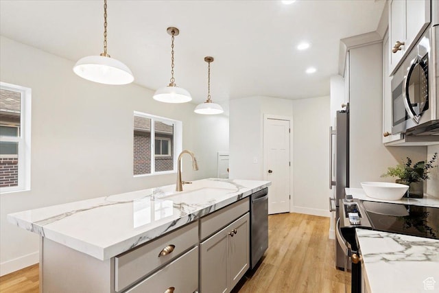 246 E 2100 S, South Salt Lake, UT 84115 - kitchen with stainless steel appliances, light wood finished floors, pendant lighting, light stone counters, and a kitchen island with sink
