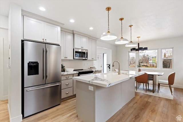 246 E 2100 S, South Salt Lake, UT 84115 - kitchen with stainless steel appliances, light wood-style floors, an island with sink, light stone countertops, and recessed lighting