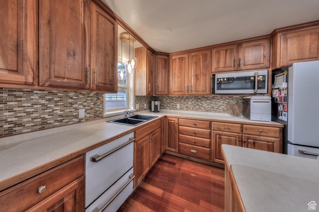 558 Winesap Cir, Moab, UT 84532 - kitchen with stainless steel microwave, dark wood-style floors, light countertops, freestanding refrigerator, and brown cabinets