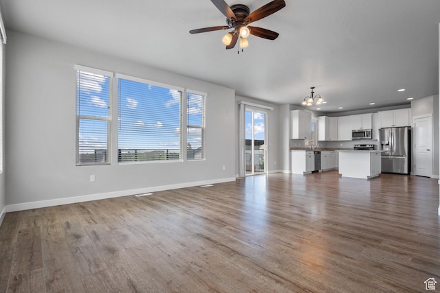 248 W Quartz Rd, Tooele, UT 84074 - unfurnished living room featuring a chandelier, baseboards, dark wood-style floors, a ceiling fan, and recessed lighting