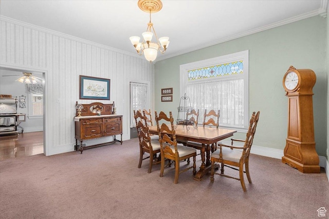 dining area with ceiling fan with notable chandelier, carpet floors, and crown molding