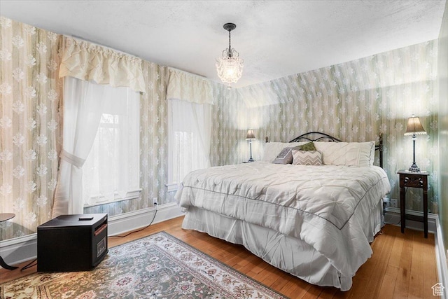 bedroom with hardwood / wood-style floors, a notable chandelier, and multiple windows